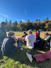 A group of students sit on the Quad lawn for an Italian club meeting.