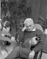 Jacques Derrida sitting in a chair with a cat on his lap