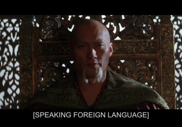 Still of TV with subtitles reading "Speaking Foreign Language"