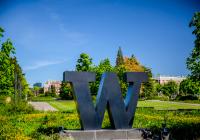 Bronze W statue at Rainier Vista looking toward campus during a sunny day.