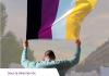 A person holds the nonbinary flag over their head.