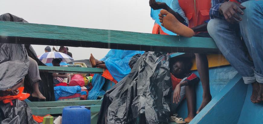 View of refugees from inside the bottom of a small, blue wooden boat